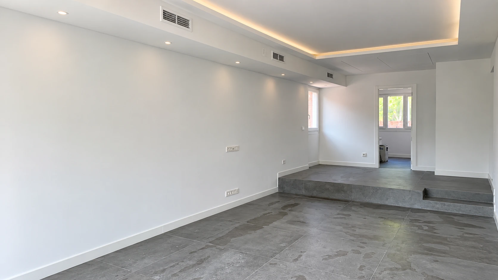 Espacio abierto terminado con techo iluminado y pavimento gris continuo
